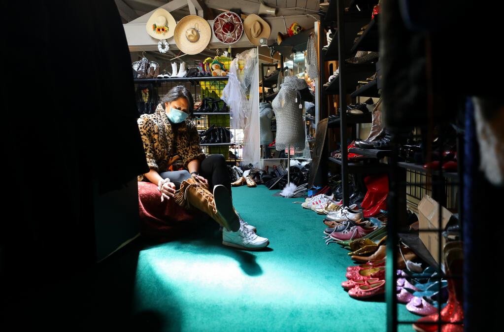 Andrea De Leon tries on a jacket and a pair of boots while shopping at Disguise the Limit costume shop in Santa Rosa on Friday, April 23, 2021.  (Christopher Chung/ The Press Democrat)
