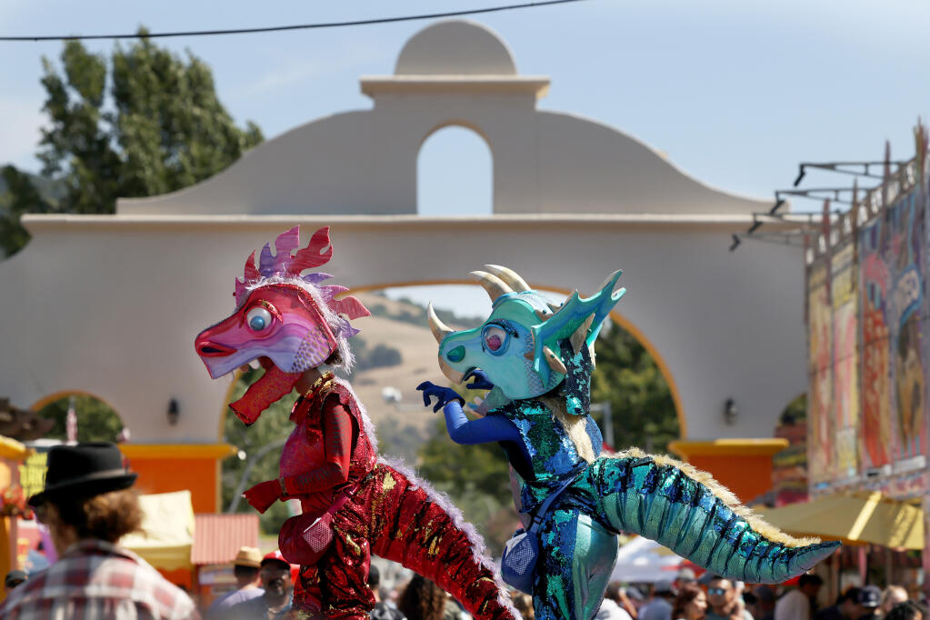 Stilt walkers  from Animal Cracker Conspiracy wear dinosaur costumes as they walk through the crowd during the final day of the Sonoma County Fair in Santa Rosa, Sunday, Aug. 13, 2023. (Beth Schlanker / The Press Democrat)
