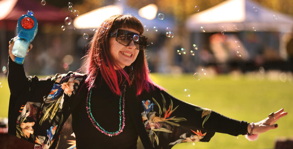 Chris Young-Ginzburg uses a bubble gun as she dances near her DJ setup at the Patchwork Show at Old Courthouse Square in Santa Rosa, Saturday, Nov. 20, 2021.  (Kent Porter / The Press Democrat) 2021