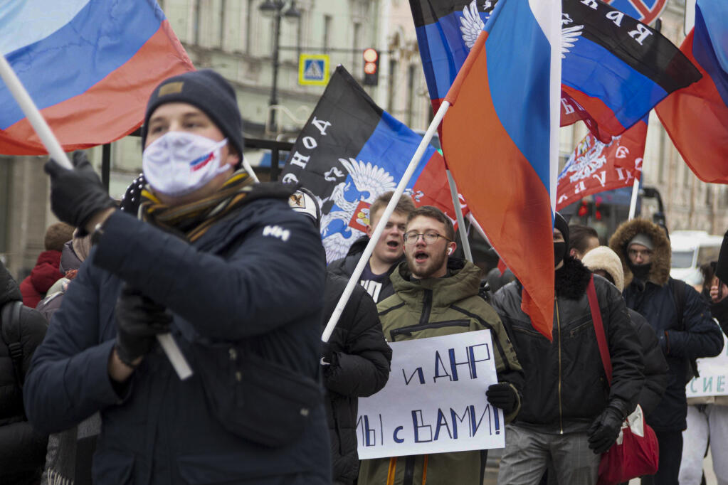Pro-Kremlin activists and students rally with Russian and Donetsk People republic flags and a poster that reads: "Donetsk Luhansk People republics we are together" celebrating the recognition of rebel-controlled regions in Donbas, at the Palace Square in St. Petersburg, Russia, Wednesday, Feb. 23, 2022. About five hundred people got together at St. Peterburg's main Palace Square and then proceeded along the streets of the city carrying flags of Russia and of the two self-proclaimed republics in Eastern Ukraine that have been recognised as independent by the Russian Government this week. (AP Photo/Ivan Petrov)