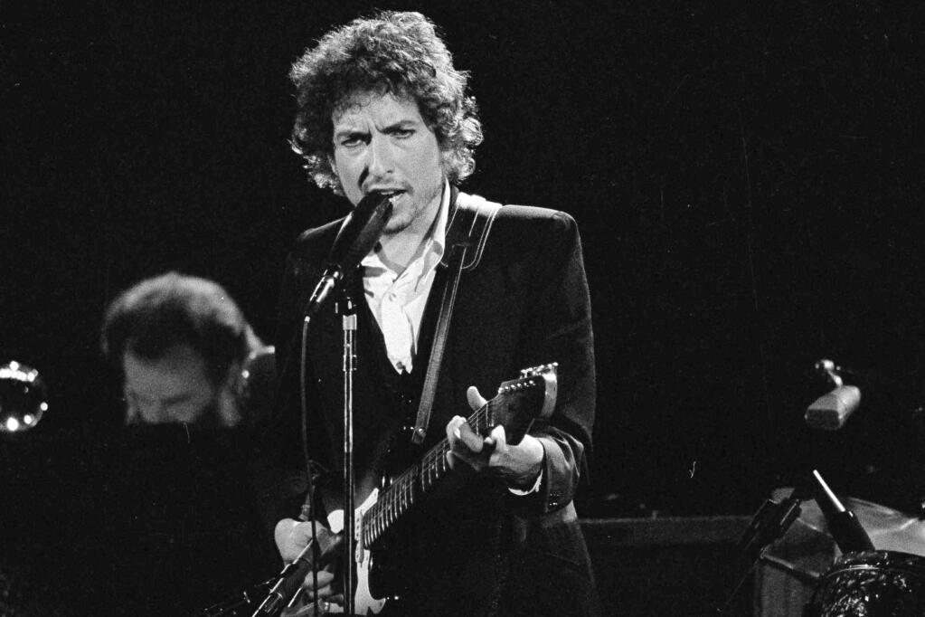 FILE - Musician Bob Dylan performs with The Band at the Forum in Los Angeles on Feb. 15, 1974. Dylan’s entire catalog of songs, which spans 60 years and is among the most prized next to that of the Beatles, is being acquired by Universal Music Publishing Group. The deal covers 600 song copyrights. (AP Photo/Jeff Robbins, File)
