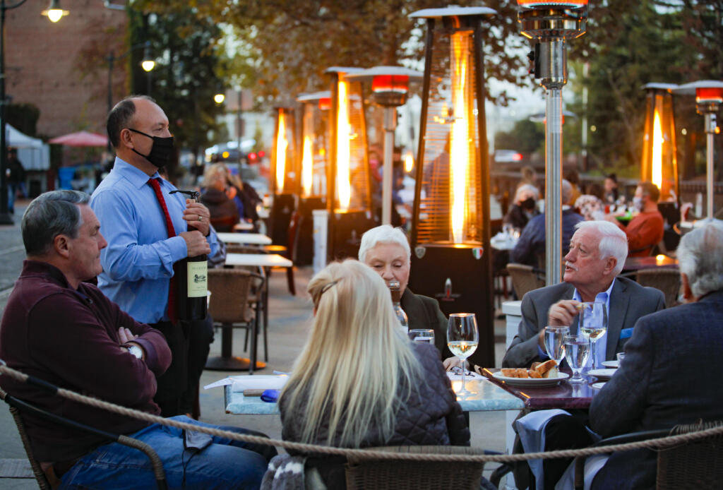 Juan Gopar, a server at Cucina Paradiso opens a bottle of wine for guests.  The downtown Petaluma restaurant serves dinner at the outdoor tables placed on Water Street.(CRISSY PASCUAL/ARGUS-COURIER STAFF)