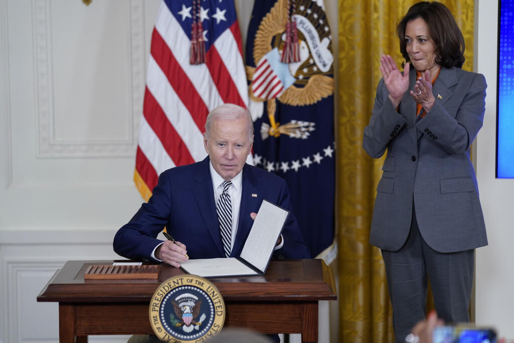 President Joe Biden signs an executive on artificial intelligence in the East Room of the White House, Monday, Oct. 30, 2023, in Washington. Vice President Kamala Harris applauds at right. (AP Photo/Evan Vucci)