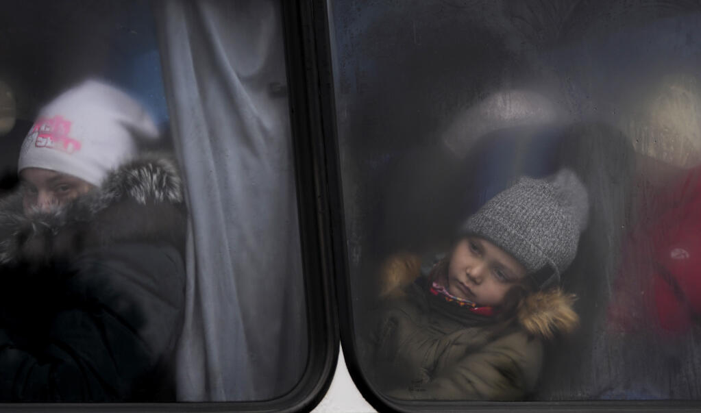 Two children, traveling with others fleeing Ukraine, look out of the window of a bus near the border crossing in Medyka, Poland, Saturday, March 5, 2022. (AP Photo/Markus Schreiber)