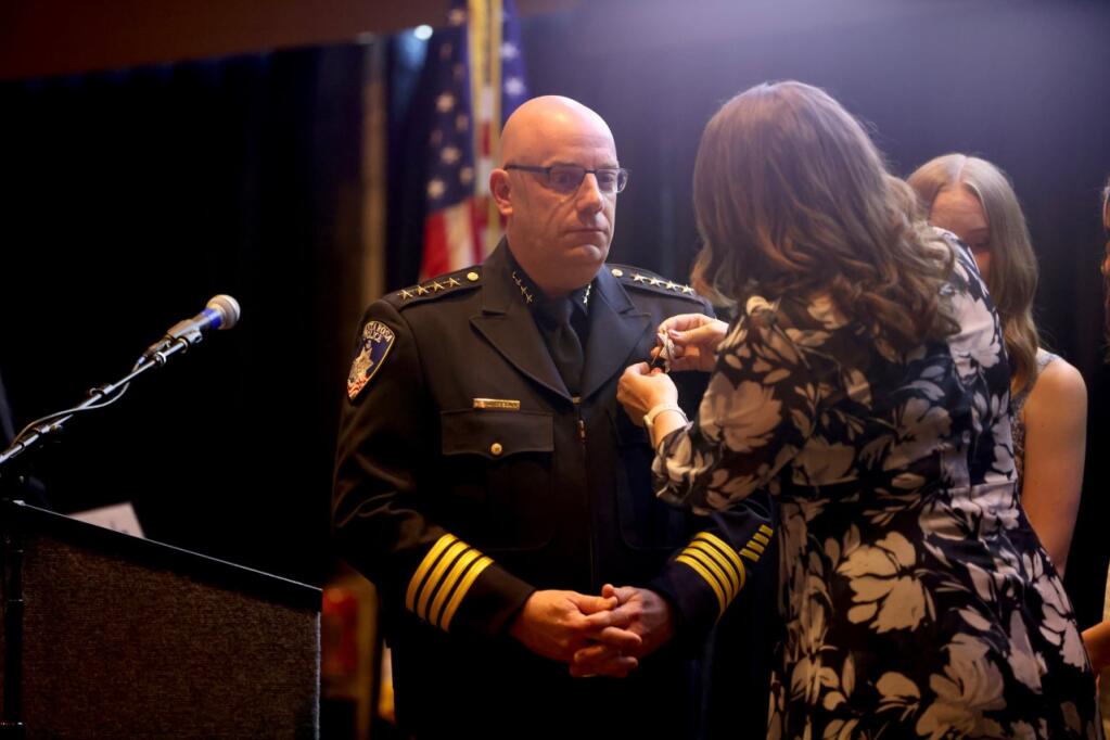 John Cregan stands as his wife, Angela, attaches a pin to his chest Monday during a ceremony at the Luther Burbank Center for the Arts, July 25, 2022. Cregan was sworn in as Santa Rosa's police chief. (Beth Schlanker / The Press Democrat)