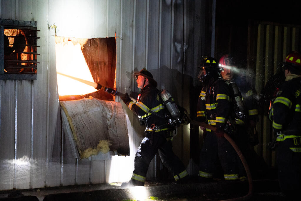 Firefighters drown the fire with water after cutting out an access hole to the structure in the early hours of Saturday, Feb. 11, 2023 at 21885 Eighth Street East in Sonoma. (Nicholas Vides / For The Press Democrat)