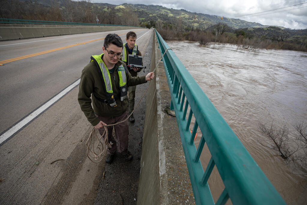 USGS Hydro Technician John Chan, left, pulls a sensor through the water of the Russian River at Highway 128 outside Geyserville along with Field Office Chief Andrew Watson as they measure the flow of the river, Monday, Feb. 5, 2024. (Chad Surmick / The Press Democrat)