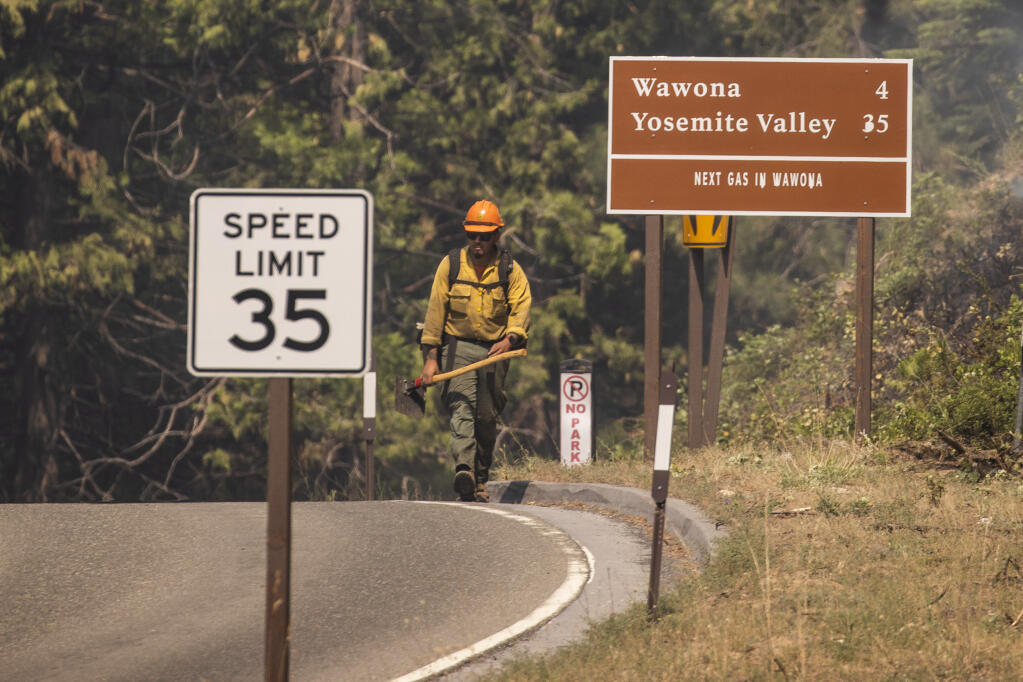 A firefighter walks past a backfire while battling the Washburn Fire in Yosemite National Park, Calif.,Monday, July 11, 2022. (Stephen Lam/San Francisco Chronicle via AP)