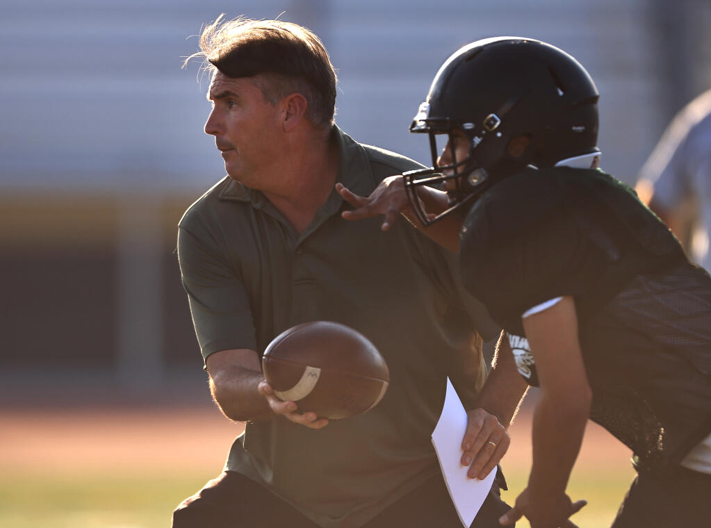 Windsor High School head football coach Paul Cronin hands the ball off to running back as he runs through offensive formations during practice Tuesday, Sept. 7, 2021 in Windsor. (Kent Porter / The Press Democrat)