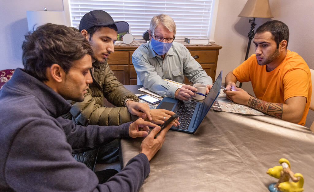 Paul O’Rear, with First United Methodist Church, helps recent Afghan refugees Suliman Dawood, right, his brother Ibrahim and their brother-in-law Yahia Sakhizada, far left, register for class at the junior college in their new home in Santa Rosa on Friday, January 07, 2022.  (Photo by John Burgess/The Press Democrat)