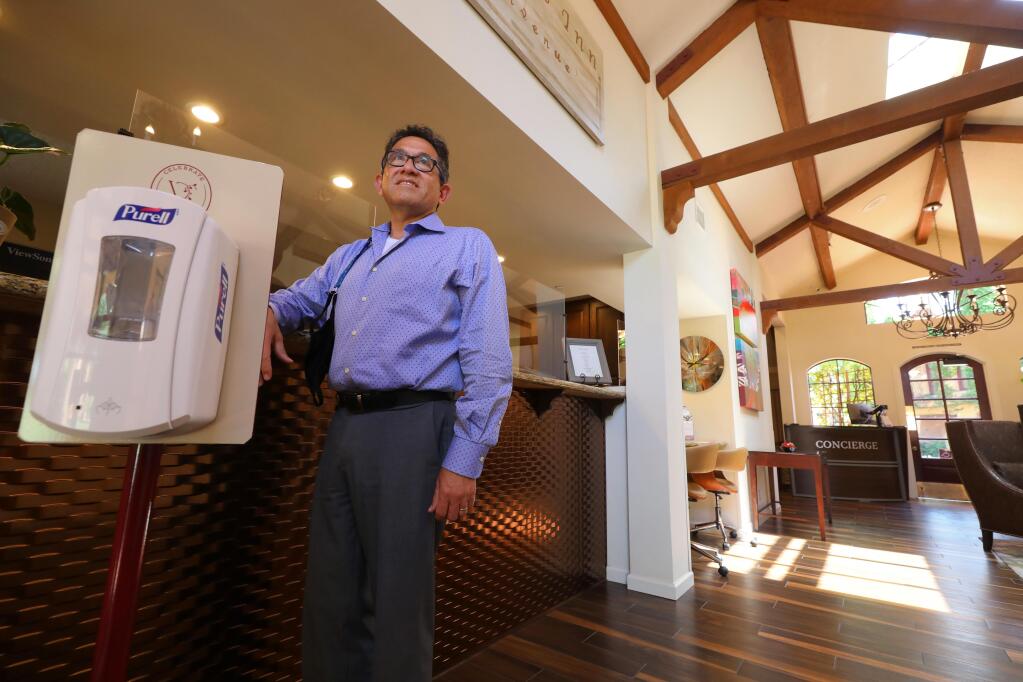 Vintners Resort general manager Percy Brandon has had a hand sanitizer station and plexiglass installed at the check-in area of the hotel in order to keep guests and staff safe.(Christopher Chung/ The Press Democrat)