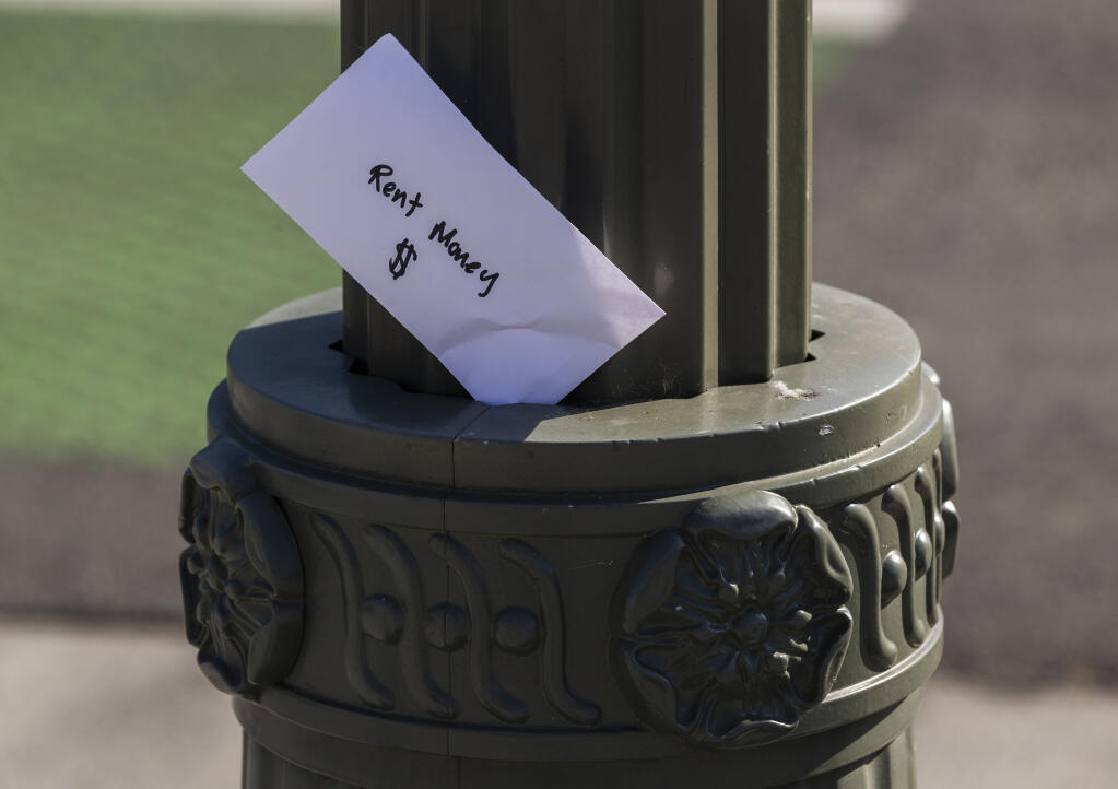 File - A paper envelope was written with the words "Rent Money $" is left tucked in a lighting pole in the Boyle Heights east district of the city of Los Angeles, Wednesday, April 1, 2020.  The California Senate advanced a bill Monday, Aug. 31, 2020, to ban evictions through January for people who can't pay their rent due to the coronavirus. (AP Photo/Damian Dovarganes, File)