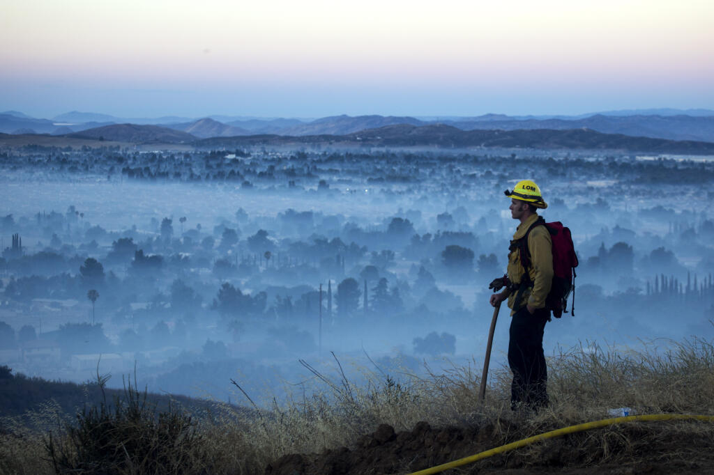 FILE - In this Aug. 1, 2020, file photo, a firefighter watches a brush fire at the Apple fire in Cherry Valley, Calif. (AP Photo/Ringo H.W. Chiu, File)