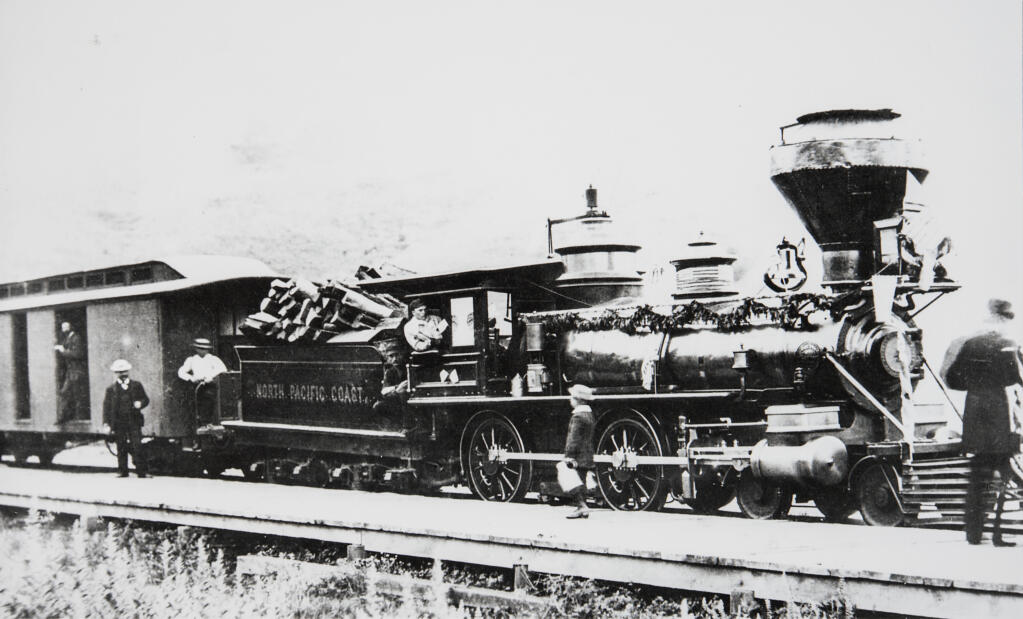 A North Pacific Coast Railroad train pulled by Engine Number 4, decorated with garland, stopped in Duncans Mills in 1877.  The tender, behind the cab, is piled high with wood and the train engineer, center, is in the cab. (Sonoma County Library)