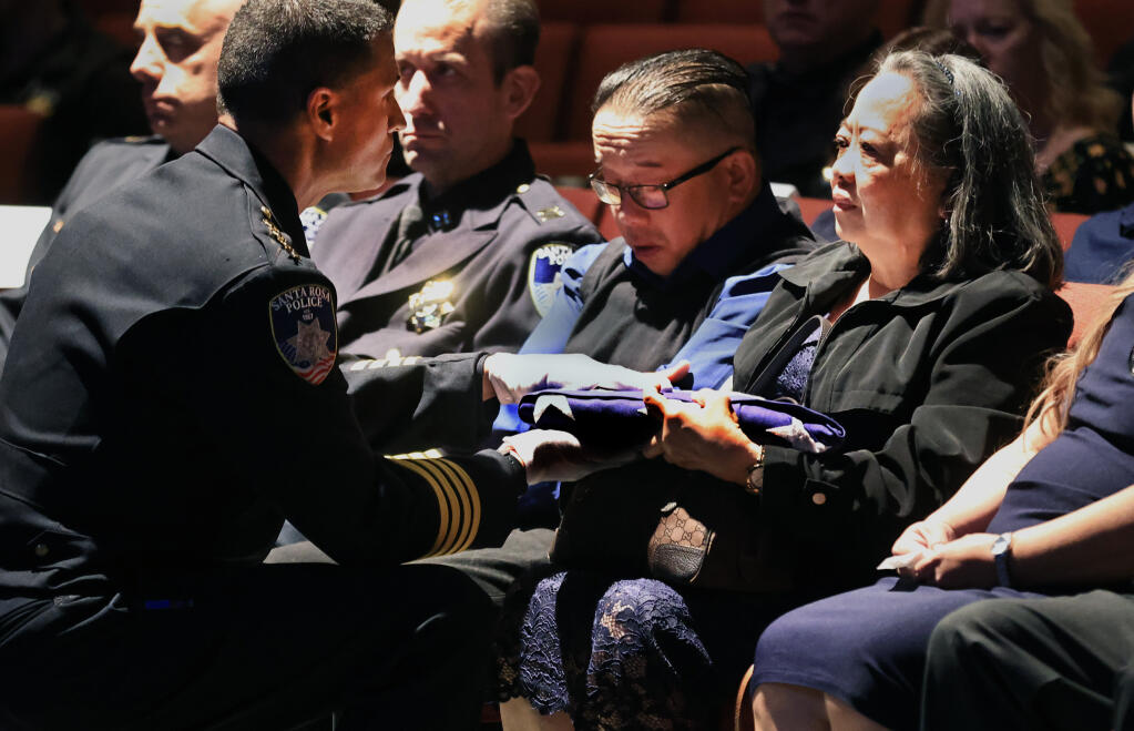 Santa Rosa Police Chief Rainer Navarro hands the flag honoring Marylou Armer to her mother, Susan Hernandez, during a memorial, Thursday, July 8, 2021 at the Luther Burbank Center for the Arts. At left is brother-in-law Ronnie Hernadez.   (Kent Porter / The Press Democrat)