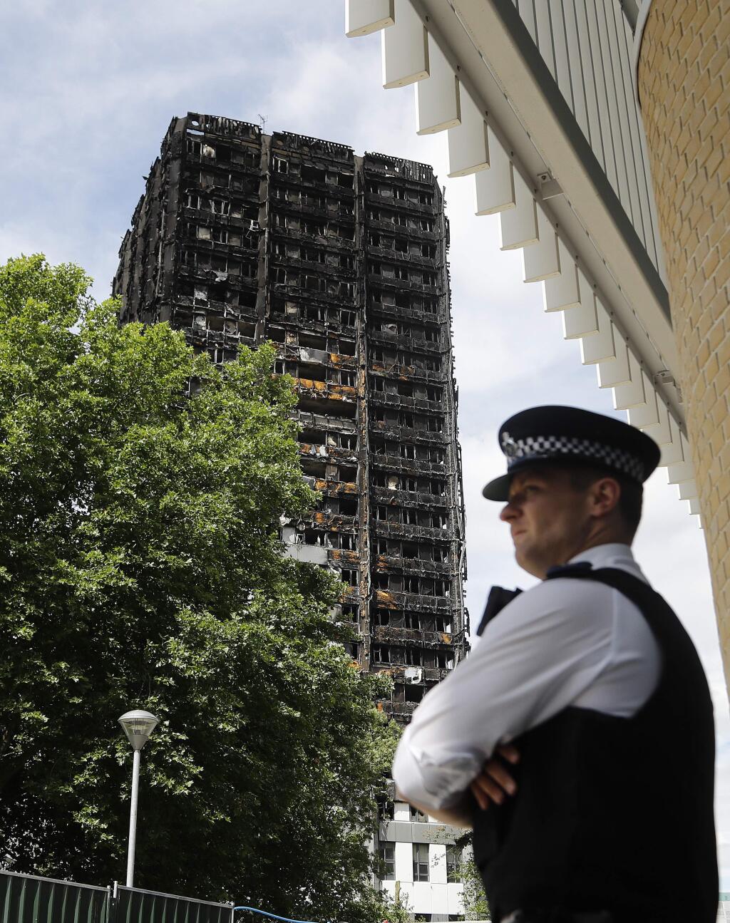 A police officer stands near to the burnt Grenfell Tower apartment building standing testament to the recent fire in London, Friday, June 23, 2017. British officials have ordered an immediate examination Friday, into a fridge-freezer that is deemed to have started the fire in the 24-storey high-rise apartment building early morning of June 14th, and the outside cladding of the building which is thought to have helped spread the fire, according to police, leaving dozens dead.(AP Photo/Frank Augstein)