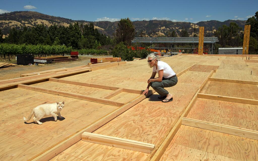 Bree Klotter and the family cat stand amidst the boards denoting where walls in her new home in Redwood Valley will stand when finished. Klotter's home was one of 190 homes lost in the October 2017 wildfires in the community just north of Ukiah. (photo by John Burgess/The Press Democrat)