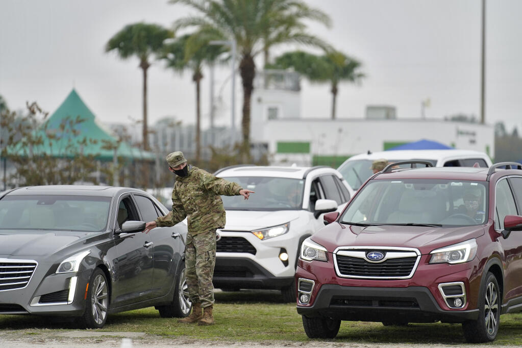 A member of the Florida National Guard directs people waiting in line for the coronavirus vaccine at an outdoor vaccination site at Lakewood Ranch Wednesday, Feb. 17, 2021, in Bradenton, Fla. (AP Photo/Chris O'Meara)