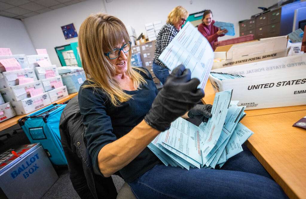 Christie Roberts arranges the orientation of mail in ballots for a counting machine at the Sonoma County Registrar of Voters office in Santa Rosa, Wednesday, Nov. 9, 2022. (John Burgess/Press Democrat)