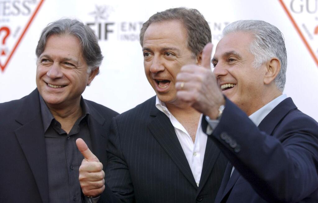 FILE - In this May 9, 2002 file photo, Guess Inc. founders and brothers, from left, Armand, Paul and Maurice Marciano arrive at the company's 20th anniversary party in Los Angeles. Guess Inc. says its co-founder Paul Marciano is stepping down after a company-commissioned investigation of allegations of sexual harassment and assault. The company announced in a filing Tuesday, June 12, 2018, with the Securities and Exchange Commission that Marciano is resigning immediately as executive chairman of the Guess board, and his brother and co-founder Maurice Marciano will take over. (AP Photo/Chris Pizzello, File)