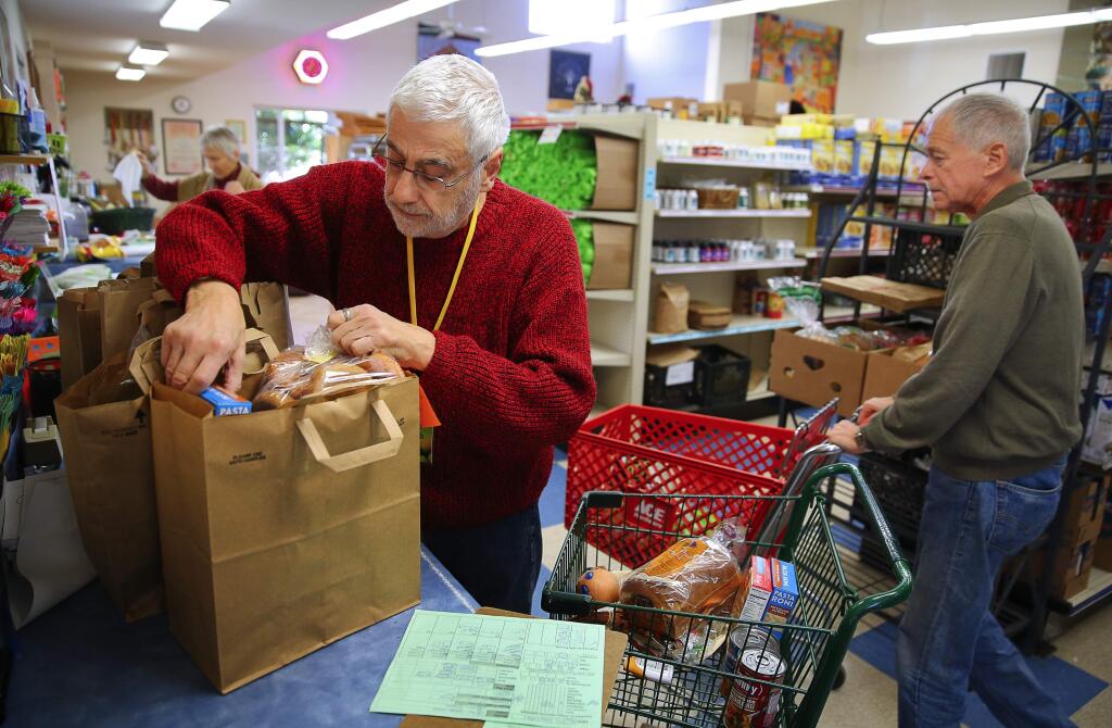 Bob Mascolo, left, and Gregory Venegas fill out orders for clients at Food For Thought, in Forestville, on Thursday, December 22, 2016. (Christopher Chung/ The Press Democrat)