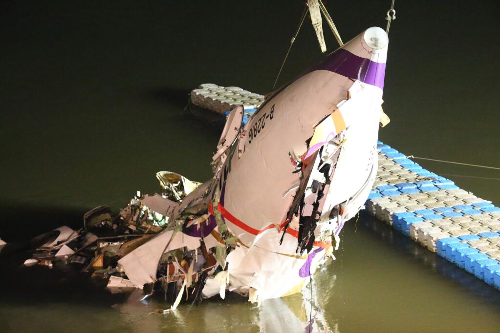 The mangled fuselage of a TransAsia Airways commercial plane is dragged to the river bank after it crashed in Taipei, Taiwan, Wednesday, Feb. 4, 2015. The Taiwanese commercial flight with 58 people aboard clipped a bridge shortly after takeoff and crashed into a river in the island's capital of Taipei on Wednesday morning. (AP Photo) TAIWAN OUT