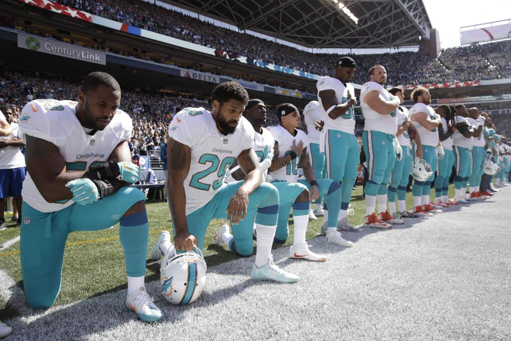 In this Sept. 11, 2017 file photo, from left, the Miami Dolphins' Jelani Jenkins, Arian Foster, Michael Thomas, and Kenny Stills, kneel during the singing of the national anthem before a game against the Seattle Seahawks in Seattle. Miami Dolphins players who protest on the field during the national anthem this season could be suspended for up to four games under a new team policy issued to players this week. The policy obtained by The Associated Press on Thursday, July 19, 2018 classifies anthem protests as conduct detrimental to the club, punishable by suspension without pay, a fine or both. (AP Photo/Stephen Brashear, File)