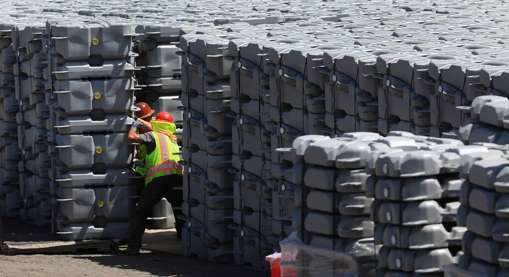 David Gomes, left, and Walker Rotherham unload solar panel floats that will be floated in to one Windsor's effluent ponds, Wednesday, June 5, 2019. (Kent Porter / The Press Democrat) 2019