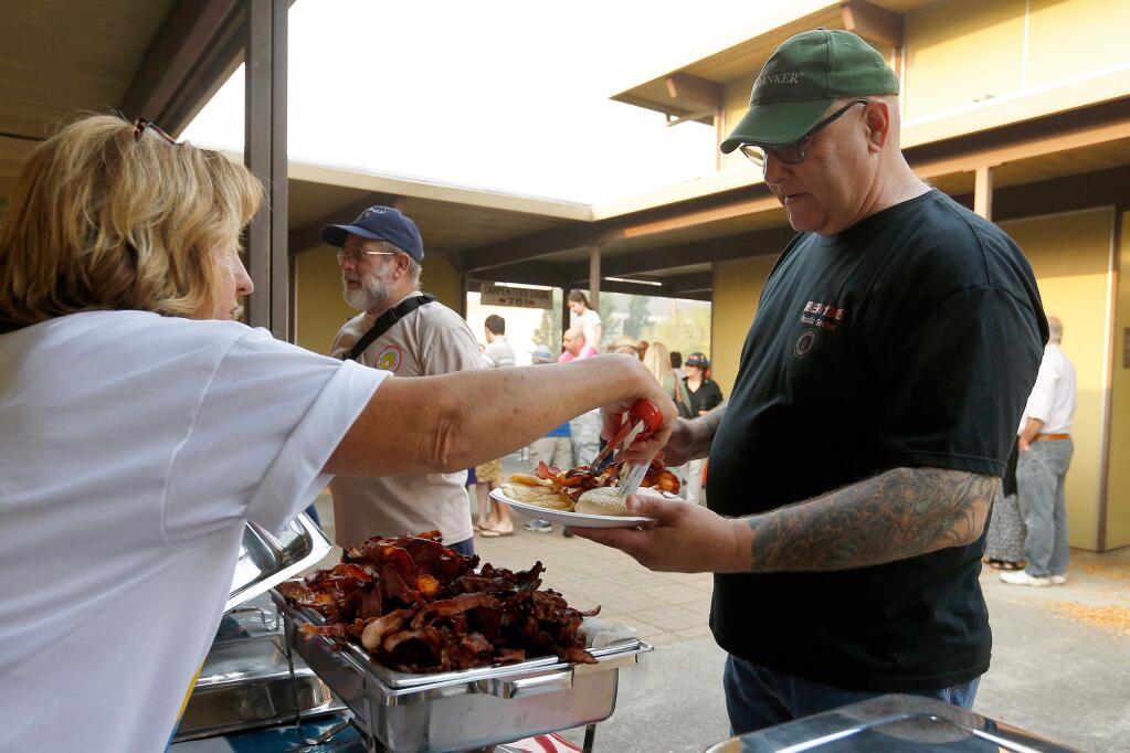 JV Macor, right gets a serving of bacon from Sydney Moy during the North Bay Labor Council's annual pancake breakfast in Santa Rosa, California, on Monday, September 4, 2017. (Alvin Jornada / The Press Democrat)