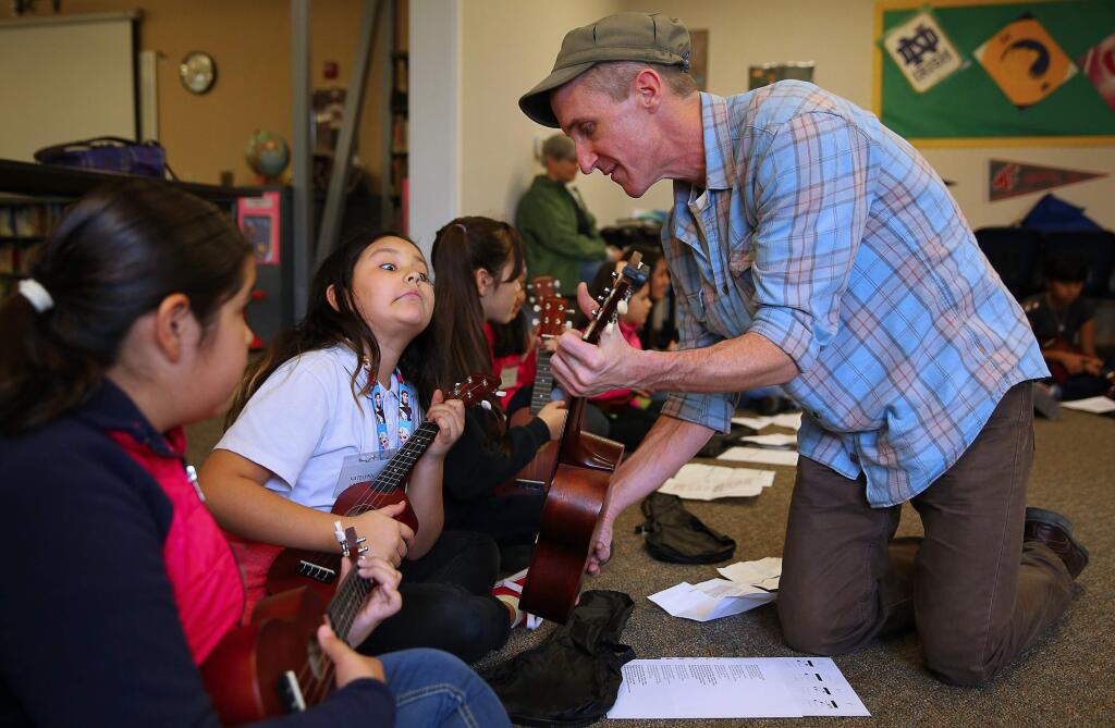 Music teacher Andrew DeVeny shows Katelynn Valencia the proper finger placement for a note while teaching students how to play the ukulele at Bellevue Elementary School in Santa Rosa, on Thursday, Jan. 21, 2016. The ukulele lessons were part of the Wells Fargo Center for the Arts' education outreach program, and students will be joining the Wellington International Ukelele Orchestra during a performance this week. (Christopher Chung / The Press Democrat)