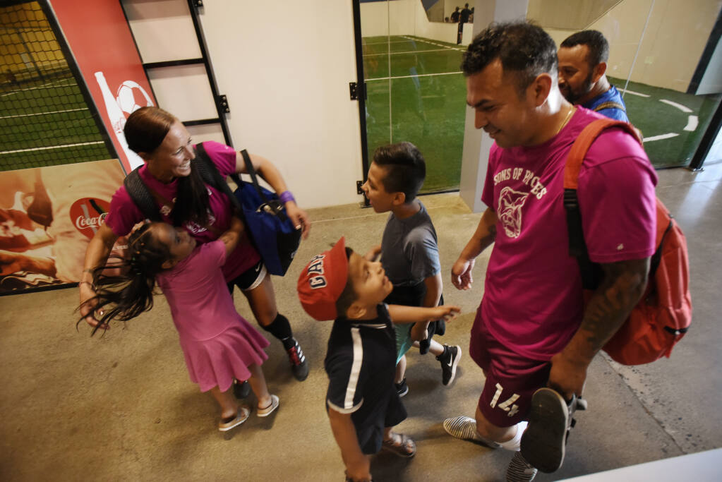 Sons Of Pitches player Roberto Hernandez, right, with his three children, from left, Dayra, 4, hugging fellow player Crystal Howard, Bernardo, 6, and Juan Pablo, 9, after an adult league indoor soccer game at Epicenter Sports and Entertainment in Santa Rosa, California on Friday, July 2, 2021. (Erik Castro/for The Press Democrat)