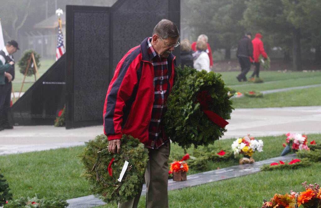 Photos by Bill Hoban/Index-TribuneRemembering departed veteransSaturday was the annual Wreaths Across America where Christmas wreaths are placed on the graves of veterans. About 100 people turned out at the Sonoma Veterans Memorial Park on a fog-shrouded morning. Above, Capt. Mike Morrison, with the Civil Air Patrol, left, and Major Joe Fernandes, USAF, ret., place one of the wreaths on a stand to commemorate the Air Force. At right, a volunteer looks for graves to place his wreaths.