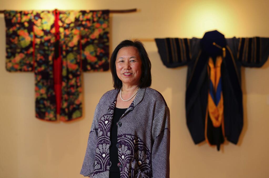 SSU President Judy Sakaki, flanked by her grandmother's kimono, left, and her own UC Berkeley doctoral robes, at an exhibit for her Investiture in the campus library. (Christopher Chung/ The Press Democrat)