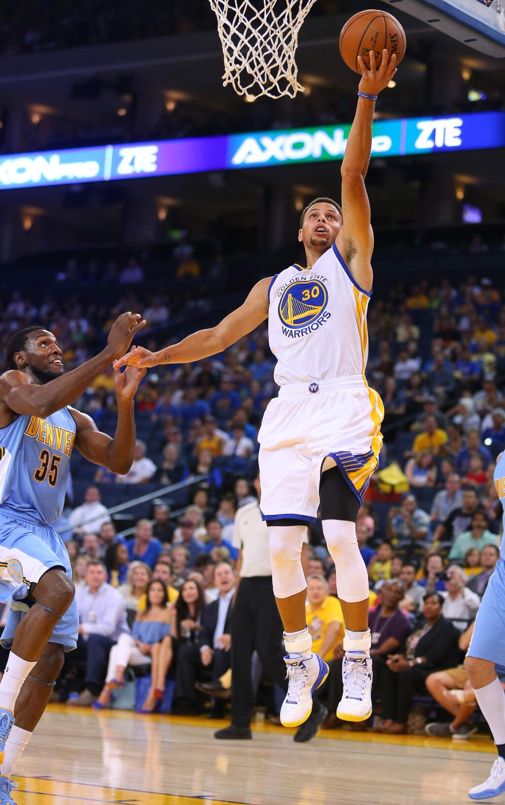 Warriors guard Stephen Curry lays the ball in against Nuggets forward Kenneth Faried during their preseason game in Oakland on Tuesday, October 13, 2015. (Christopher Chung/ The Press Democrat)