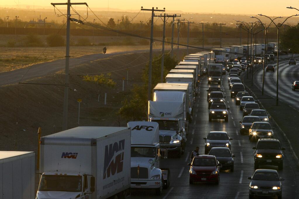 FILE- In this April 9, 2019, file photo, trucks wait to cross the border with the U.S. in Ciudad Juarez, Mexico. In a surprise announcement that could compromise a major trade deal, President Donald Trump announced Thursday that he is slapping a 5% tariff on all Mexican imports to pressure the country to do more to crack down on the surge of Central American migrants trying to cross the U.S. border. (AP Photo/Christian Torres, File)