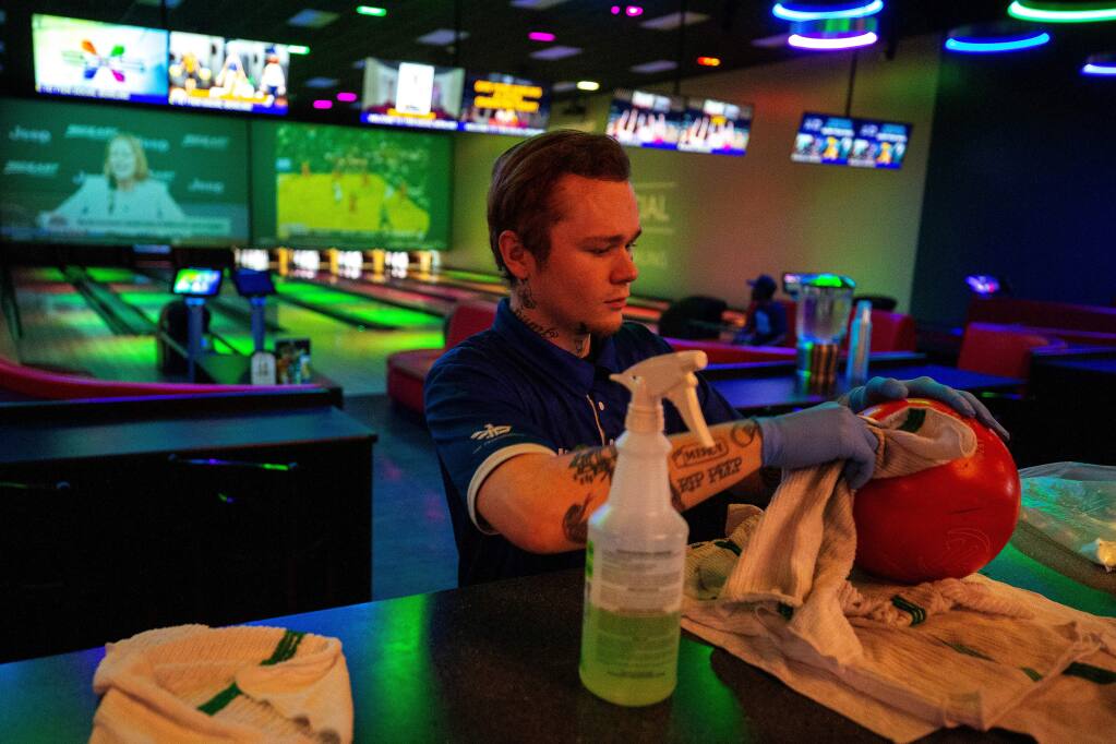 Bowling attendant James Maltby sanitizes bowling balls at 7TEN Bowling inside The Epicenter sports and entertainment complex in Santa Rosa, California, on Thursday, March 12. That business is among a growing number of local firms severely impacted by coronavirus lockdown orders that are turning to fundraisers to keep their doors open. (Alvin Jornada / The Press Democrat)