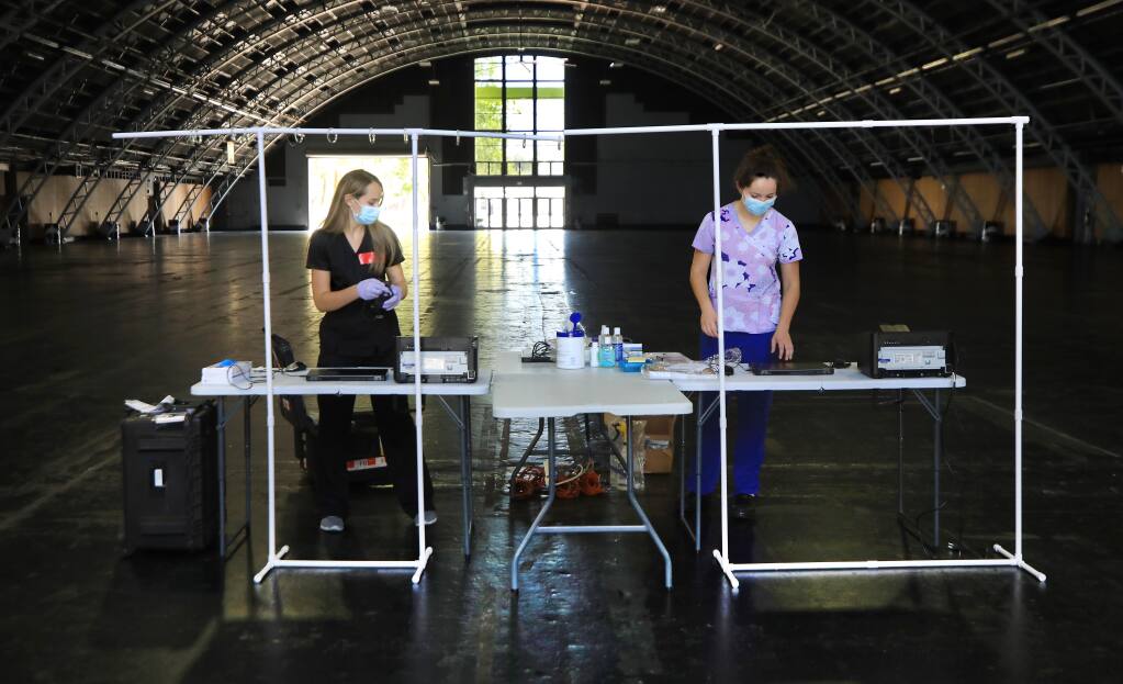 OptumServe administrative personnel Hannah Burnett, left, and Marissa Wilkins set up their new admitting desks for COVID-19 testing at the Sonoma County Fairgrounds, Thursday, July 3, 2020, in Santa Rosa. (Kent Porter / The Press Democrat)