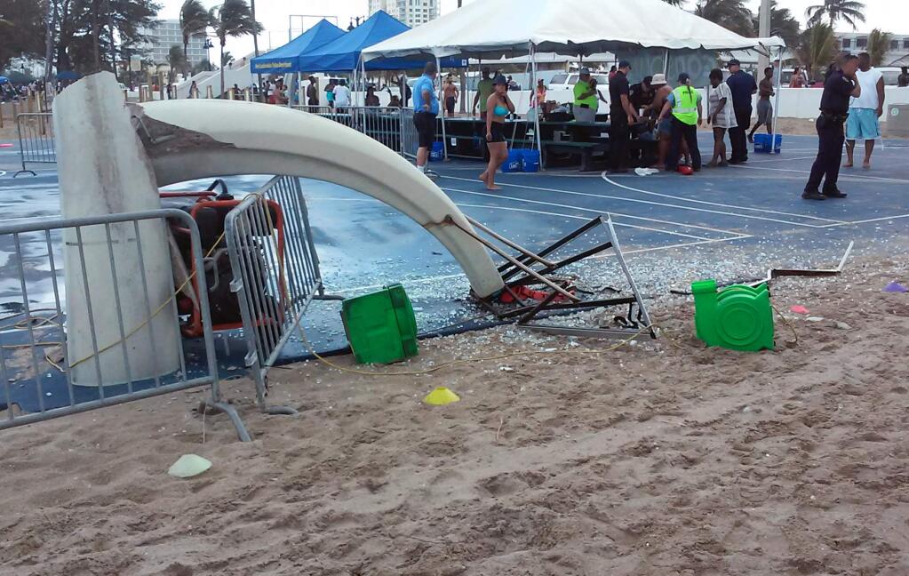 In this photo provided by Burt Osteen, glass is scattered around a toppled basketball hoop after a waterspout made landfall at Fort Lauderdale Beach, Fla. on Monday, May 25, 2015. Authorities say three children were injured when the waterspout uprooted a bounce house and sent it across a parking lot into the road. (Burt Osteen via AP)