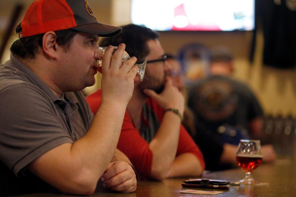 Lenny Slutsky, left, and his friend Brian Connor watch a baseball game on television as they sample local beers at Local Barrel in Santa Rosa, California, on Thursday, March 9, 2017. (Alvin Jornada / The Press Democrat)