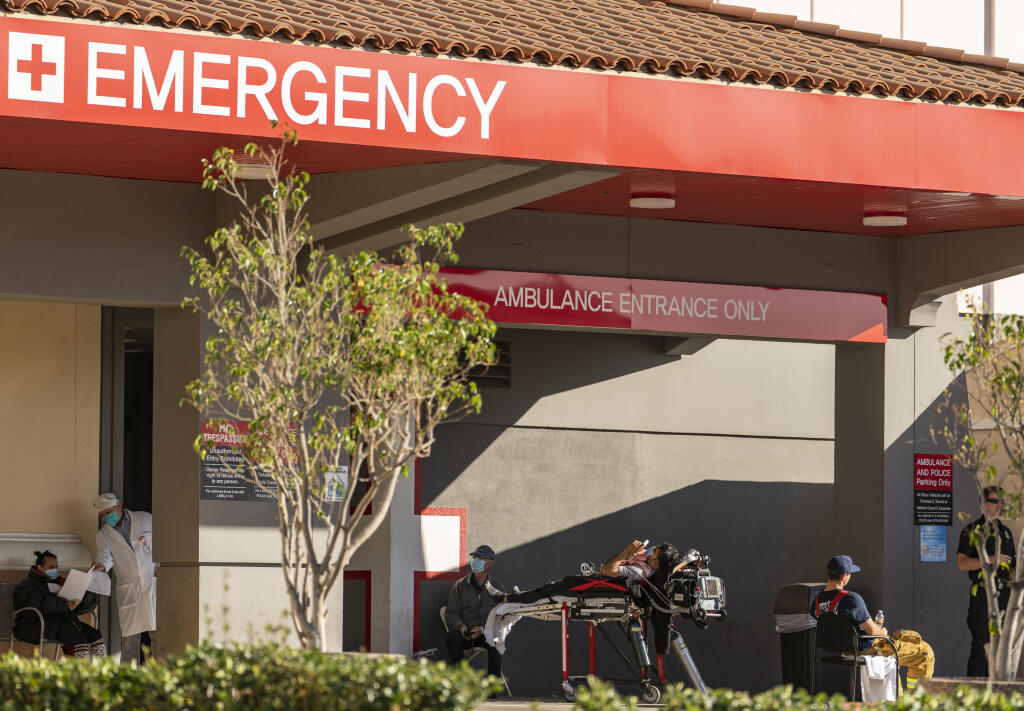 An unidentified patient receives oxygen on a stretcher Dec. 18, 2020, while Los Angeles Fire Department paramedics monitor him outside the Emergency entrance, waiting for admission at the CHA Hollywood Presbyterian Medical Center in Los Angeles. California hospitals are facing increasingly difficult decisions about which services to postpone amid a crushing load of coronavirus patients. Intensive care beds are full in Southern California and the Central Valley, with statewide availability at only 1.1%. (Damian Dovarganes / Associated Press)
