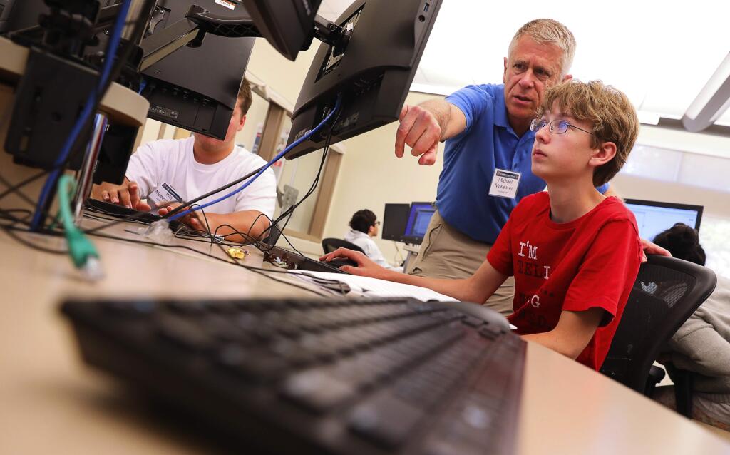 Instructor Michael McKeaver helps Cole McBeardsley with a problem during the Air Force Association's CyberPatriot Cybercamp in Petaluma on Tuesday, July 25, 2017. (Christopher Chung/ The Press Democrat)