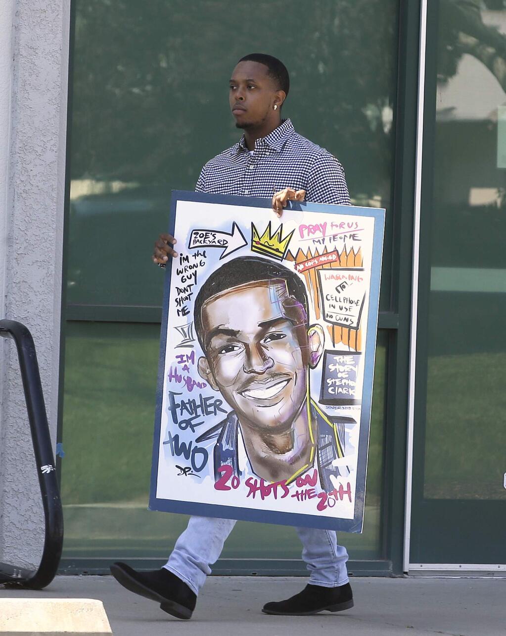 An attendee for the wake of police shooting victim Stephon Clark carries a drawing of Clark to the Bayside of South Sacramento Church, known as BOSS Church, Wednesday, March 28, 2018, in Sacramento, Calif. Clark, who was unarmed, was shot and killed by Sacramento Police Officers, Sunday, March 18, 2018. (AP Photo/Rich Pedroncelli)