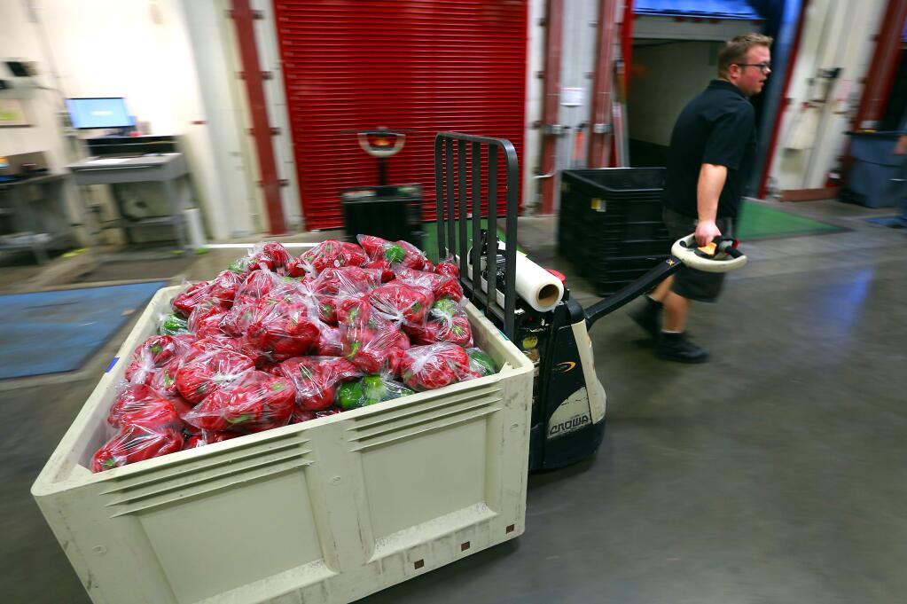 D.J. Kirchner moves a bin of bell peppers at the Redwood Empire Food Bank in Santa Rosa on Friday, Nov. 7, 2014. (JOHN BURGESS/ PD)
