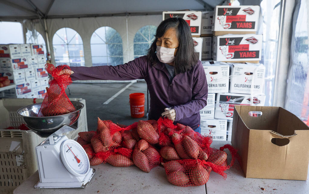 Volunteer Jeanne Allen weighs a bag of yams at the Redwood Empire Food Bank in Santa Rosa on Feb. 4, 2021. With demand for food continuing to soar amid the pandemic, the regional food bank is desperate for more volunteers.(Photo by John Burgess/The Press Democrat)