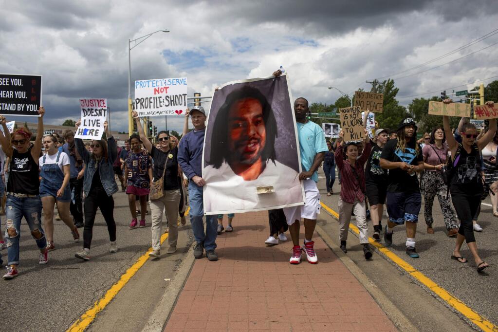 Protesters hold an image Philando Castile and march down the street during a protest, Sunday, June 18, 2017, in St. Anthony, Minn. The protesters marched against the acquittal of Officer Jeronimo Yanez, was found not guilty of manslaughter for shooting Castile during a traffic stop. (Courtney Pedroza/Star Tribune via AP)