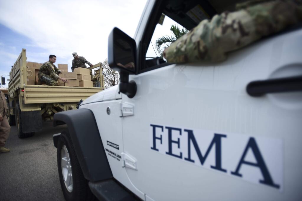 FILE - In this Oct. 5, 2017 file photo, Department of Homeland Security personnel deliver supplies to Santa Ana community residents in the aftermath of Hurricane Maria in Guayama, Puerto Rico. A government watchdog has found the Federal Emergency Management Agency wrongly released to a contractor the personal information of 2.3 million survivors of hurricanes Harvey, Irma and Maria and the California wildfires in 2017. (AP Photo/Carlos Giusti, File)