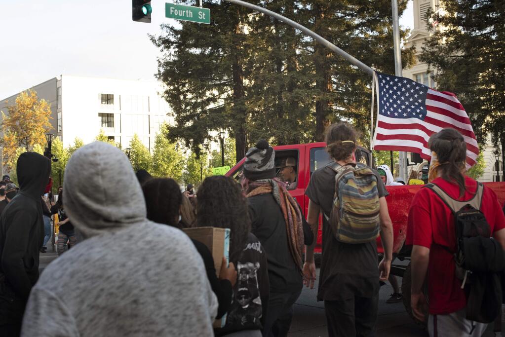 A group of protesters confront a truck with skateboards, water bottles and bare hands after the pickup drove through protesters on Fourth and Mendocino in downtown Santa Rosa on May 30, 2020. (Erik Castro/For The Press Democrat)