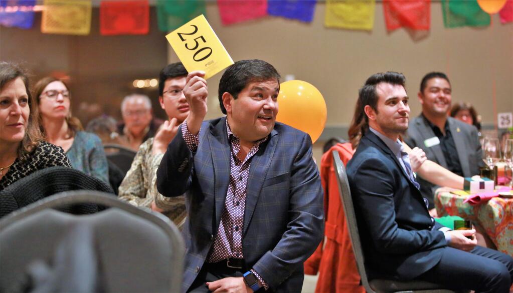 Michael Lopez bids on an auction item during Fiesta 2019, a benefit for the Elsie Allen High School Foundation, Saturday, March 9, at the Friedman Event Center in Santa Rosa. (WILL BUCQUOY/The Press Democrat)
