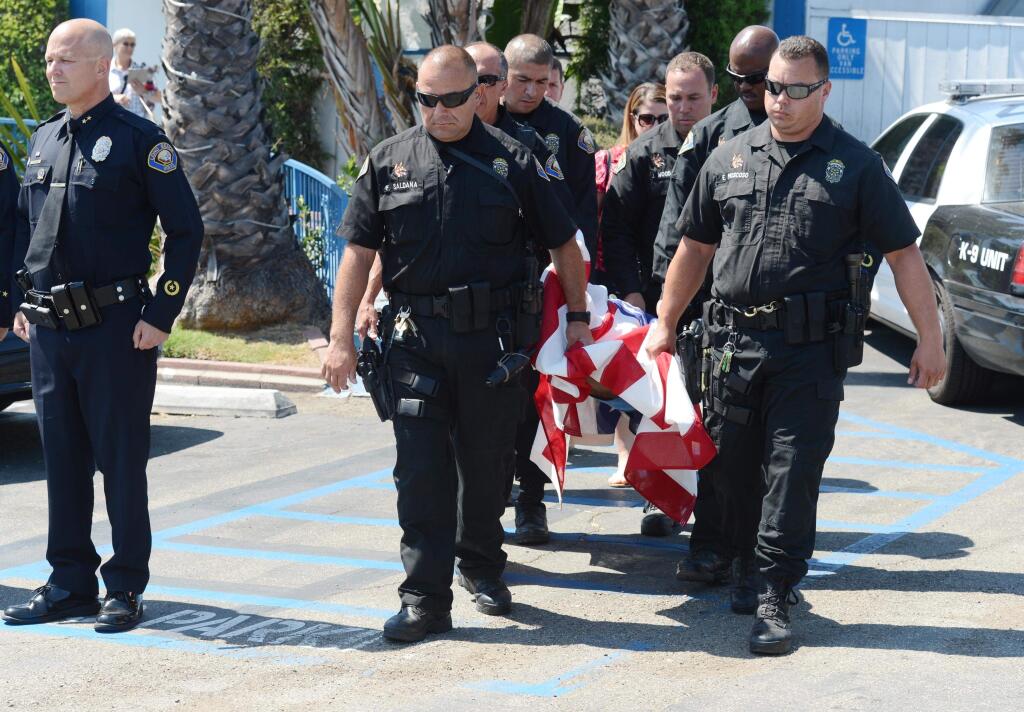 Long Beach Police Department K9 officers carry the body of LBPD K9 dog Credo from the Signal Hill Pet Hospital, who was shot and later pronounced dead at an animal hospital after he and his partner LBPD K9 officer responded to a suspect in an apartment complex in Long Beach, Calif., Tuesday, June 28, 2016. The suspect also has been shot dead after a police standoff. (Stephen Carr/The Daily Breeze via AP)