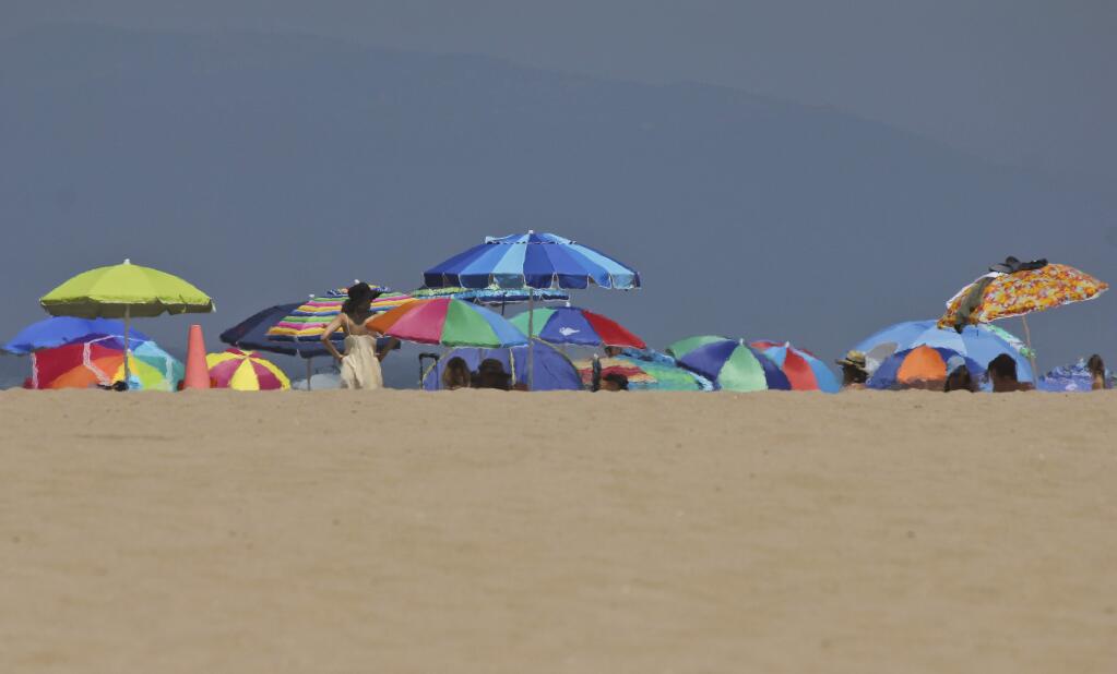 Heat rising from the sand ripples the image of umbrellas at Manhattan Beach, Calif., on Saturday, July 8, 2017. (AP Photo/John Antczak)